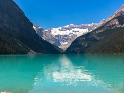 Turquoise waters of Lake Louise with reflection of snow-covered rocky mountains in Banff, Canada